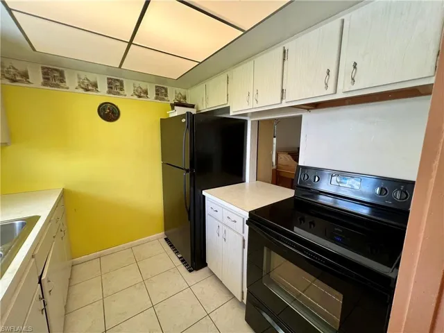 Kitchen with sink, black appliances, and light tile floors