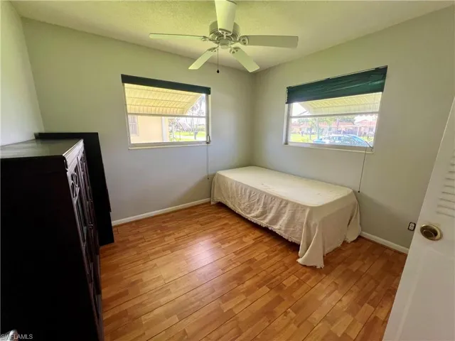 Bedroom featuring ceiling fan, light laminate/wood-style flooring, and multiple windows