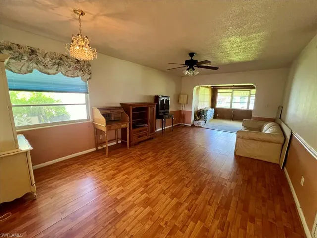 Living room/dining area featuring wood-type flooring and ceiling fan with notable chandelier