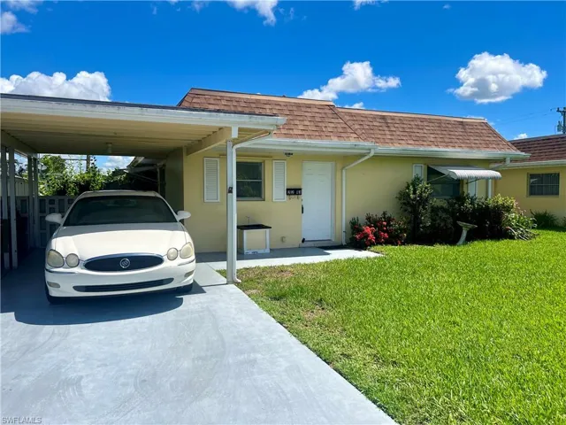 View of front of house with a front yard and a carport