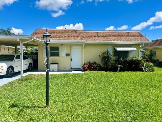 View of front facade featuring a carport and a front yard