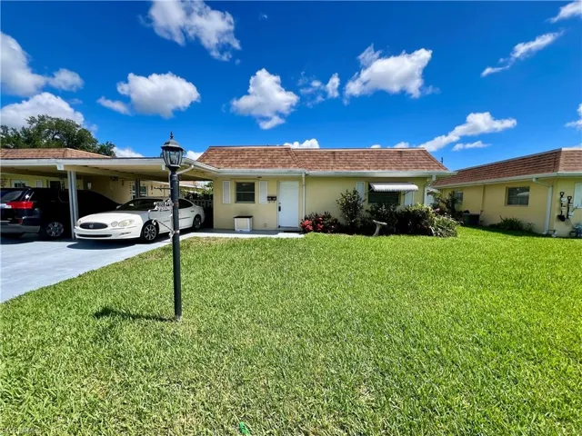 Ranch-style home featuring a front lawn and a carport
