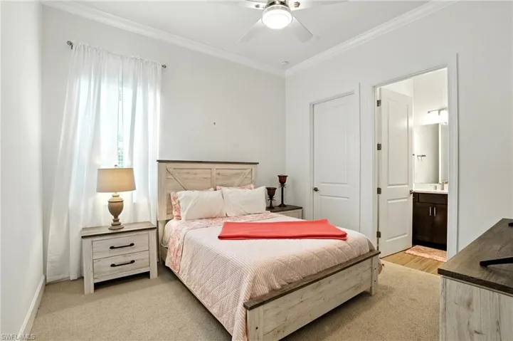 Bedroom with crown molding, ensuite bathroom, and ceiling fan