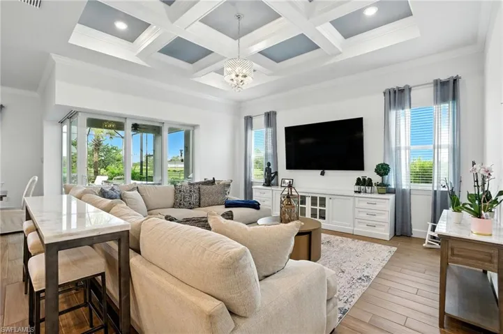 Living area featuring crown molding, beamed ceiling, a chandelier, coffered ceiling, and light wood look tile finished floors