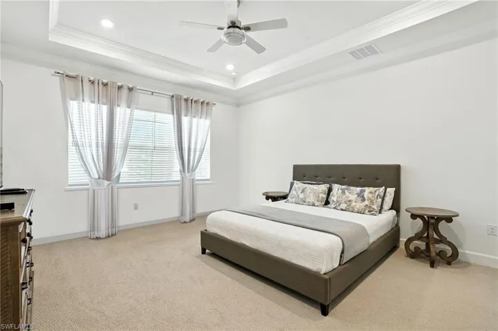 Bedroom with light colored carpet, a raised ceiling, crown molding, ceiling fan, and recessed lighting