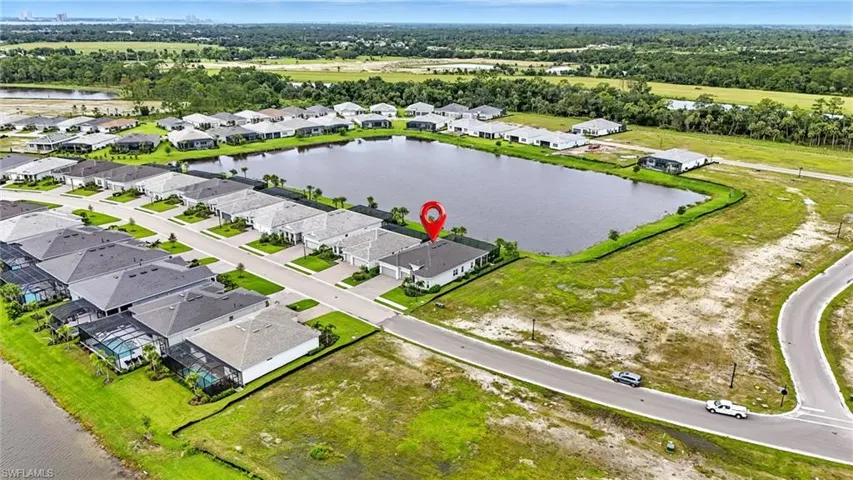 Aerial view of residential area with a large body of water and a tree filled landscape.