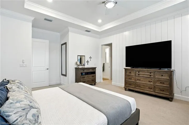 Bedroom with ornamental molding, light colored carpet, ceiling fan, recessed lighting, and wooden accent wall