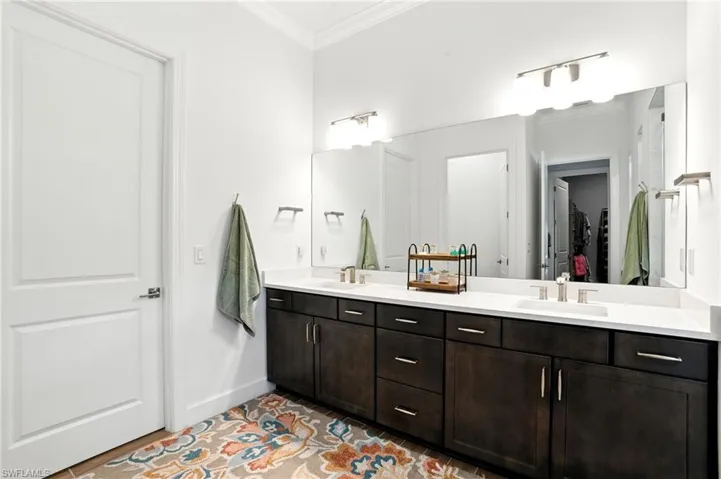 Full bathroom featuring ornamental molding, double vanity, a spacious closet, and light tile patterned floors