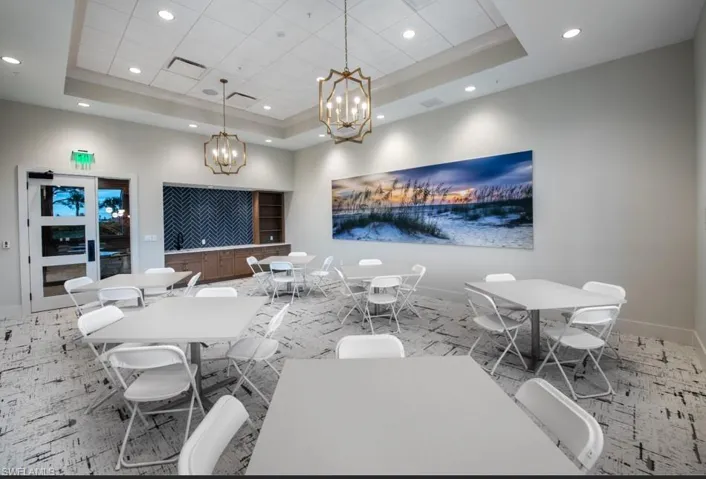Dining room with a tray ceiling, recessed lighting, and a chandelier