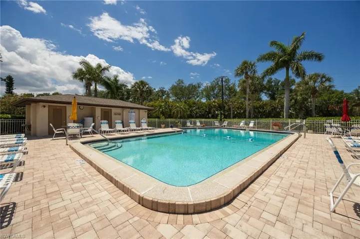 Rectangular swimming pool with integrated steps, surrounded by a paver patio and a low perimeter fence