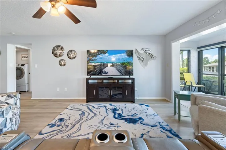 Bright living area featuring wood-finish flooring and a ceiling fan with integrated lighting