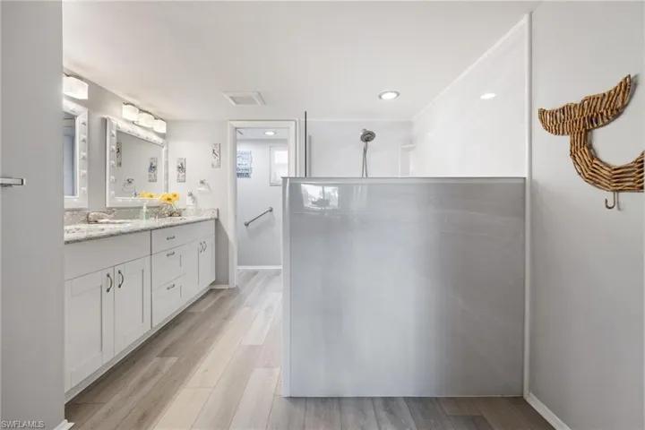 Modern bathroom featuring a dual vanity with white cabinetry and light-toned countertops