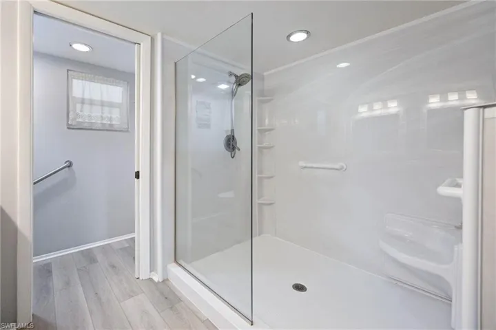 Walk-in shower with clear glass enclosure and white paneling