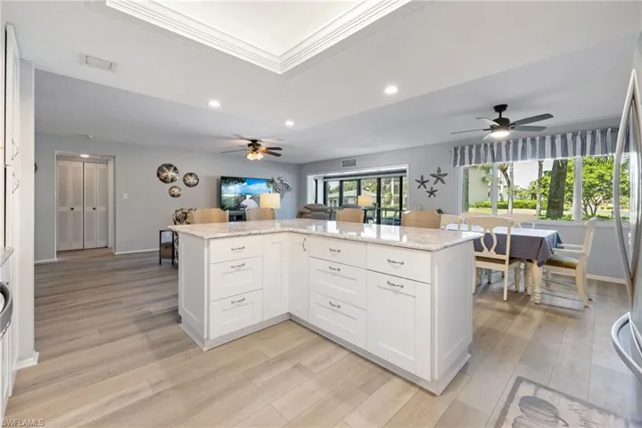 Spacious open-concept living area featuring a large kitchen island with white cabinetry and a stone countertop