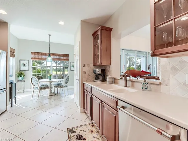 Kitchen featuring glass insert cabinets, decorative backsplash, appliances with stainless steel finishes, brown cabinetry, and recessed lighting