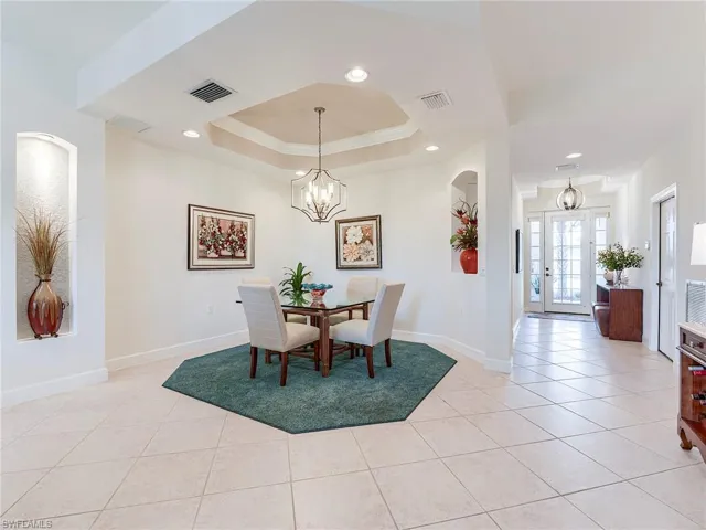 Dining room featuring a chandelier, light tile patterned flooring, recessed lighting, a raised ceiling, and crown molding