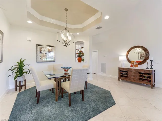 Dining room with ornamental molding, recessed lighting, light tile patterned floors, a tray ceiling, and a chandelier