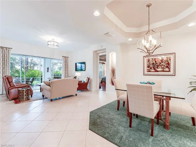 Dining room featuring a chandelier, crown molding, recessed lighting, light tile patterned floors, and a tray ceiling