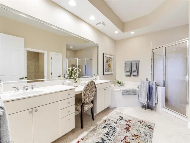 Full bathroom with double vanity, a shower stall, a garden tub, and recessed lighting