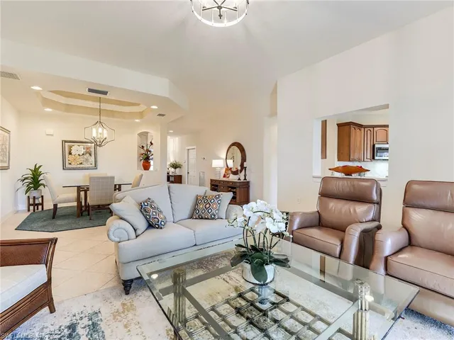 Living room with a chandelier, a raised ceiling, light tile patterned floors, and recessed lighting