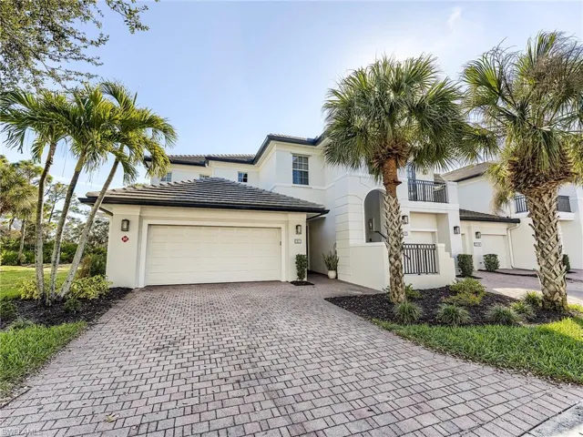 View of front of property with decorative driveway, stucco siding, and an attached garage