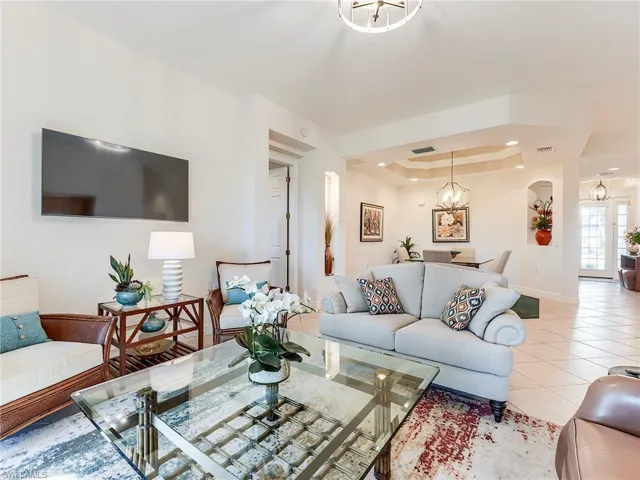 Tiled living room featuring a tray ceiling, a chandelier, and recessed lighting