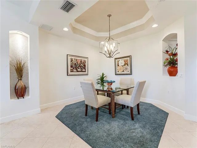 Dining space featuring crown molding, recessed lighting, light tile patterned floors, a tray ceiling, and a chandelier