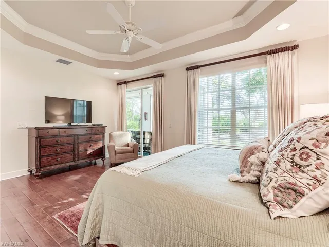 Bedroom featuring ornamental molding, hardwood / wood-style floors, access to outside, a tray ceiling, and ceiling fan