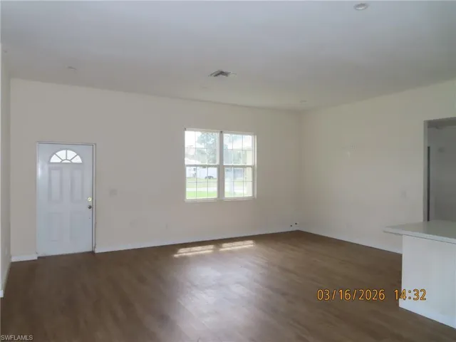 Unfurnished living room with dark wood-type flooring and baseboards