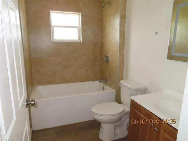 Bathroom with vanity, tub / shower combination, and dark wood-type flooring