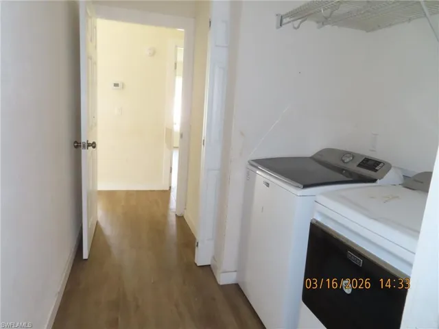 Laundry area with washing machine and clothes dryer and dark wood finished floors