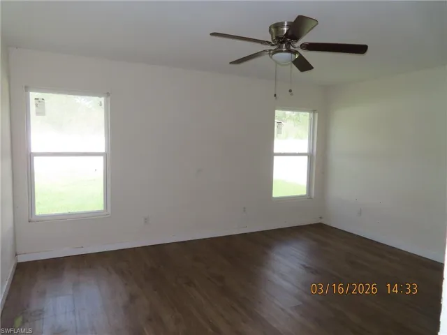 Empty room featuring dark wood-type flooring and ceiling fan