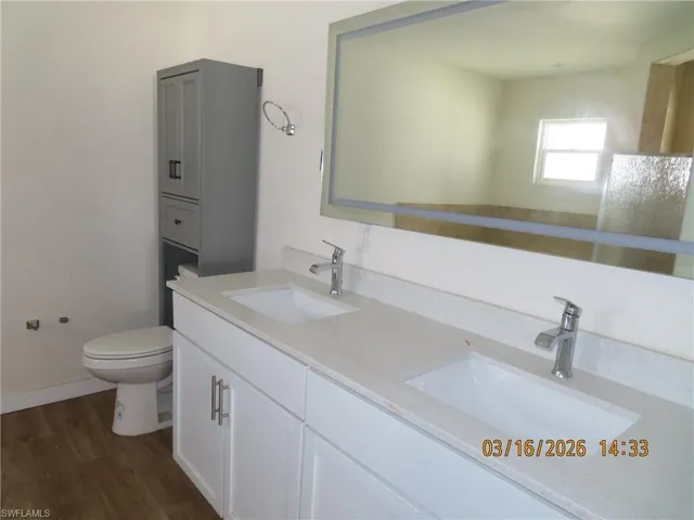 Full bathroom featuring double vanity and dark wood-style flooring