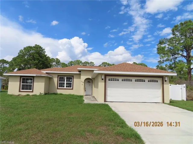 Ranch-style home with stucco siding, a garage, driveway, and a front yard