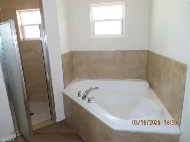 Bathroom with a shower stall, a bath, and wood finished floors