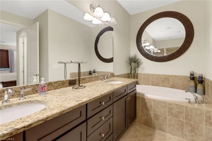 Bathroom with tile patterned floors, tiled tub, and vanity