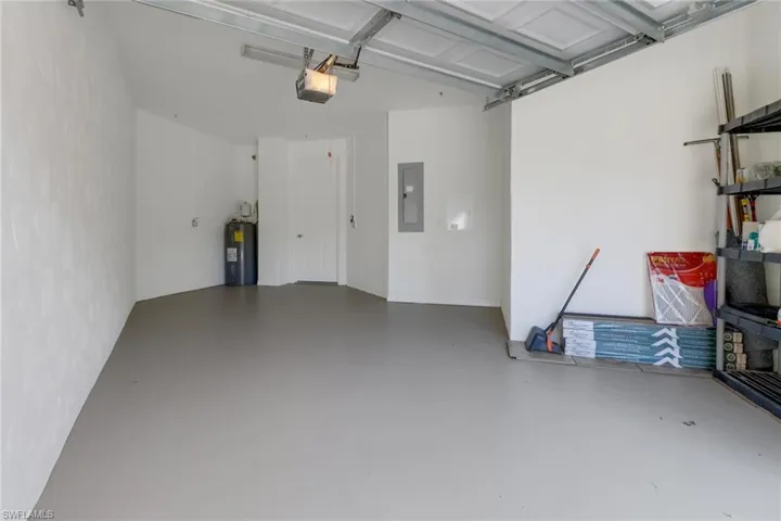 Garage with electric panel, a garage door opener, and water heater