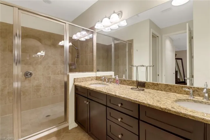 Bathroom with tile patterned floors, vanity, and a shower with door