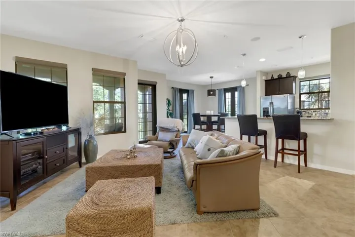 Living room featuring light tile patterned floors, a healthy amount of sunlight, and an inviting chandelier