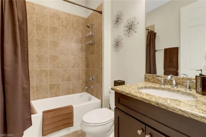 Full bathroom with vanity, shower / tub combo, and toilet
