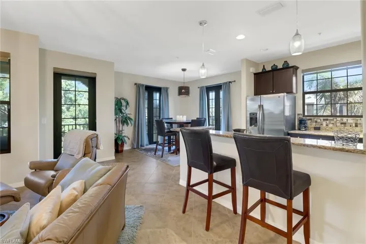 Kitchen with stainless steel fridge, pendant lighting, dark brown cabinets, and a healthy amount of sunlight