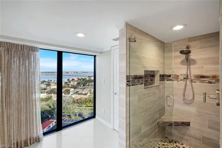 Master Bath w/an exploding view of the river, ceiling to floor glass wall. Custom updated walk in shower w/deco tiles