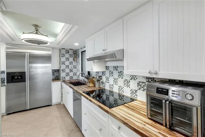 Natural wood counters, lge size refrig/freezer, smooth range top, tiled backsplash