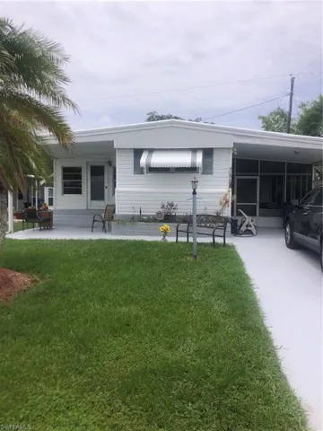 Rear view of house with a carport and a lawn