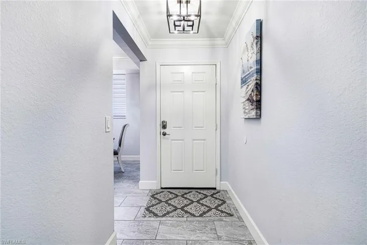 Entryway featuring a notable chandelier and ornamental molding