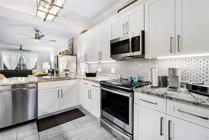 Kitchen featuring backsplash, white cabinets, and appliances with stainless steel finishes