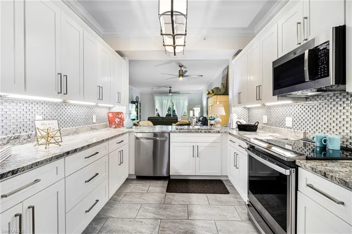 Kitchen featuring kitchen peninsula, stainless steel appliances, ceiling fan, decorative light fixtures, and white cabinetry