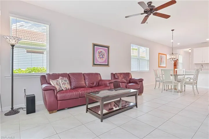Living area with light tile patterned flooring, a chandelier, ceiling fan, and recessed lighting