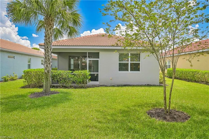 Rear view of house featuring stucco siding, a tile roof, a lawn, and a sunroom