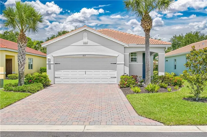 Mediterranean / spanish home featuring stucco siding, a tiled roof, decorative driveway, an attached garage, and a front yard